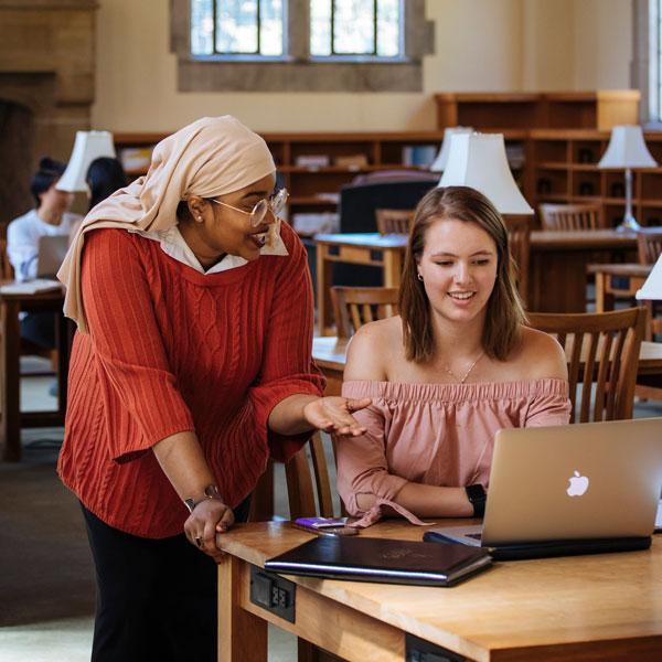 two students over computer smiling